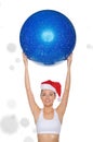 Smiley asian woman in Santa cap holds fitball under snow Royalty Free Stock Photo