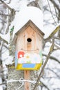 Smiley birdhouse. Birdhouse in the form of a funny face on the tree. Handmade wooden nesting box covered in snow. Winter landscape