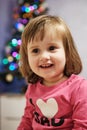 Smiley Cute baby Girl in a pink long sleeve In Blur Christmas lights Background