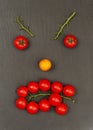 Smiley face with a angry expression. Laying out parts of a human face with vegetables, namely tomatoes and tomato branches