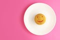 Smiley face cookies in a white plate on a pink background, top view, copy space Royalty Free Stock Photo