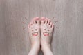 Smiley Face Drawn on Toes. Close Up Female Barefoot On Wooden Floor Background
