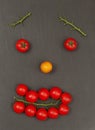 Smiley face with a happy expression. Laying out parts of a human face with vegetables, namely tomatoes and tomato branches