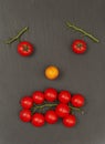 Smiley face with a sad expression. Laying out parts of a human face with vegetables, namely tomatoes and tomato branches