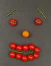 Smiley face with a sad expression. Laying out parts of a human face with vegetables, namely tomatoes and tomato branches