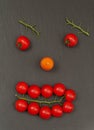 Smiley face with a watchful expression. Laying out parts of a human face with vegetables, namely tomatoes and tomato branches