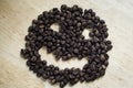 The smiley is formed from coffee beans on a light wooden background