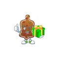 Smiley gingerbread bell cartoon character holding a gift box Royalty Free Stock Photo