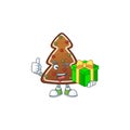 Smiley gingerbread tree cartoon character holding a gift box Royalty Free Stock Photo