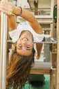 Smiley girl with long hair upsidedown in a swing at the park in Royalty Free Stock Photo