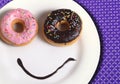 Smiley happy face made on dish with donuts eyes and chocolate syrup as smile in sugar and sweet addiction nutrition Royalty Free Stock Photo