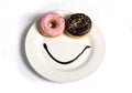 Smiley happy face made on dish with donuts eyes and chocolate syrup as smile in sugar and sweet addiction nutrition Royalty Free Stock Photo