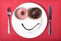 Smiley happy face made on dish with donuts eyes and chocolate syrup as smile in sugar and sweet addiction nutrition Royalty Free Stock Photo