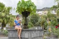 Smiley Lady sitting in a stone fountain relaxing with portable device downloading from internet. Teen student with dark hair