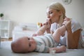 Smiley mother playing with her baby boy at home.