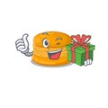 Smiley orange macaron cartoon character having a gift box