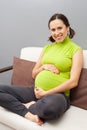 Smiley pregnant woman sitting on sofa Royalty Free Stock Photo