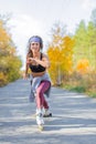 Girl roller in big headphones skating in the autumn park. Royalty Free Stock Photo