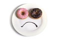 Smiley sad face made on dish with donuts as eyes and chocolate syrup mouth in sugar sweet addiction diet and nutrition