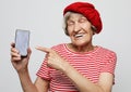 Smiley senior woman is holding a new smartphone in her hand.