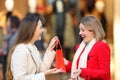 Smiley shopper giving a gift to a friend in a mall