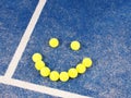 Smiley of Tennis balls on a blue artificial grass court