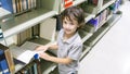 Smiley white boy with the book and the bookshelf at background Royalty Free Stock Photo