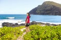 Smilig teen girl looking over shoulder, standing by rocky beach Royalty Free Stock Photo