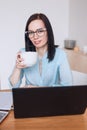 Smiliing woman drinking coffee while working online from home Royalty Free Stock Photo