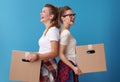 Female roommates with a cardboard boxes standing back to back