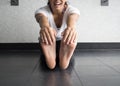 Smiling active woman grabbing her feet to stretch hamstrings in the studio