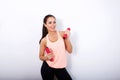 Smiling active woman lifting weights against white background