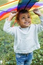 smiling adorable african american kid holding rainbow kite above head