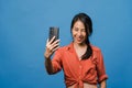 Smiling adorable Asian female making selfie photo on smart phone with positive expression in casual clothing and stand isolated on Royalty Free Stock Photo