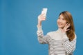 Smiling adorable Asian female making selfie photo on smart phone with positive expression in casual clothing and stand isolated on Royalty Free Stock Photo