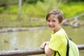 smiling adorable boy with a backpack in the park near the river. Royalty Free Stock Photo