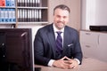 Smiling adult CEO at his desk in office