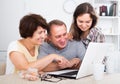 Daughter with parents searching documents on laptop