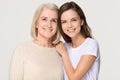 Smiling adult daughter and old mother bonding isolated on background