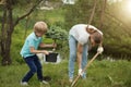 Smiling adult father and his son planting a tree outdoors in park. Royalty Free Stock Photo