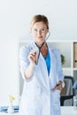 smiling adult female doctor in white coat examining by stethoscope