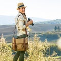 Smiling adventure woman hiker hiking in Tuscany with binoculars