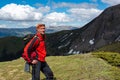 Smiling adventurer with backpack stands on a green mountain mead