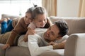 Smiling daddy relaxing on sofa with two daughters on back. Royalty Free Stock Photo