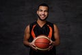 Smiling African-American basketball player in sportswear isolated over dark background. Royalty Free Stock Photo