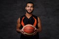 Smiling African-American basketball player in sportswear isolated over dark background. Royalty Free Stock Photo