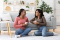 Smiling african american besties having conversation while drinking coffee