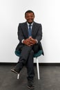 Smiling african american black man in business suit sitting on chair with crossed fingers Royalty Free Stock Photo