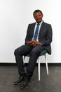 Smiling african american black man in business suit sitting on chair with crossed fingers Royalty Free Stock Photo