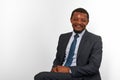 Smiling african american black man in business suit sitting on chair isolated on white background Royalty Free Stock Photo